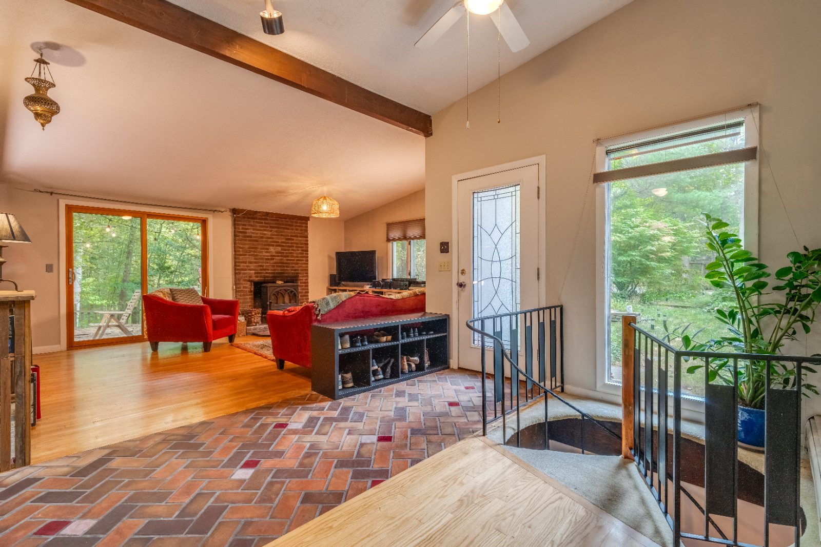 Entry and living room with wood stove, vaulted beam and herringbone brick floor