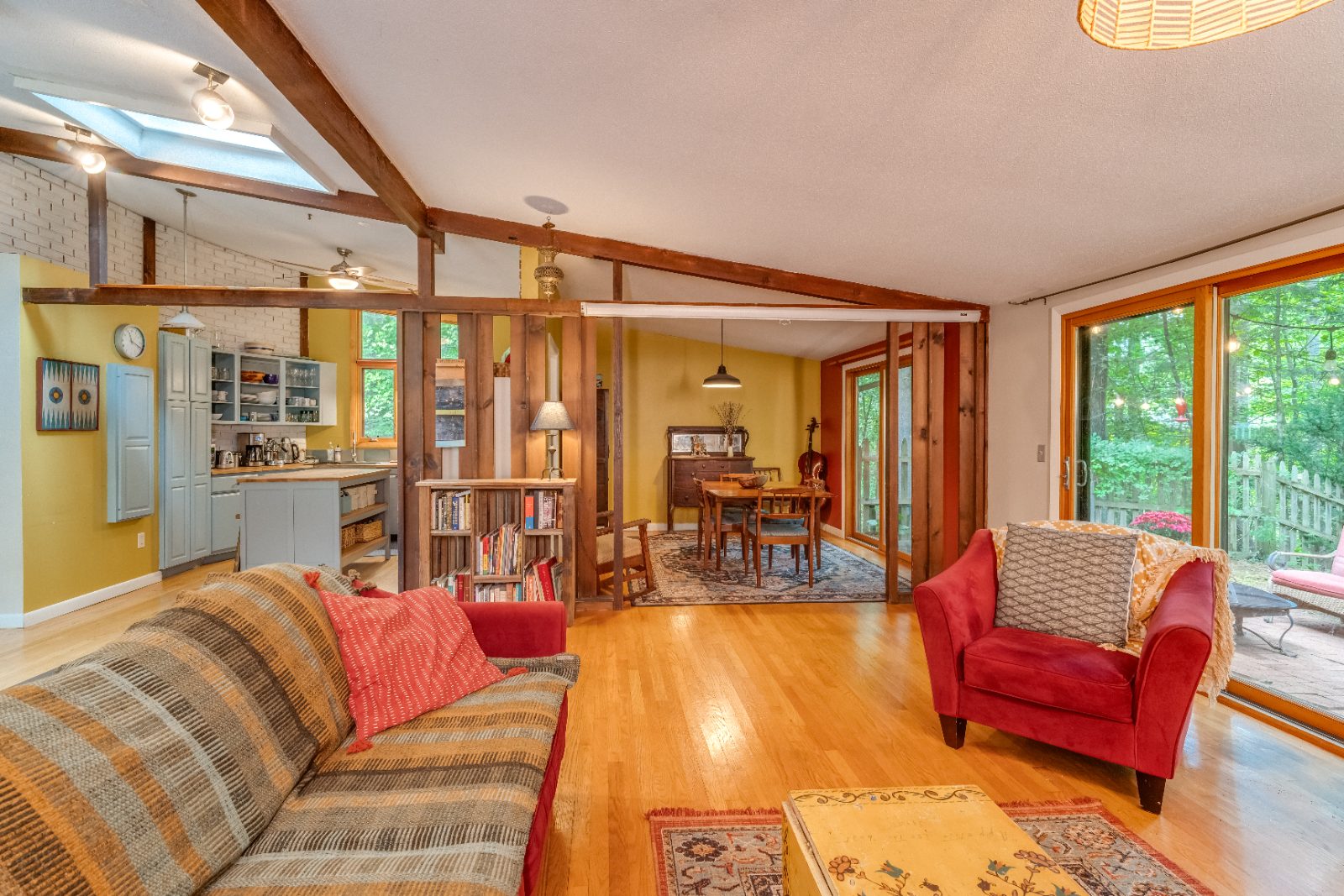 Open living room with vaulted beamed ceiling, skylight and hardwood floors